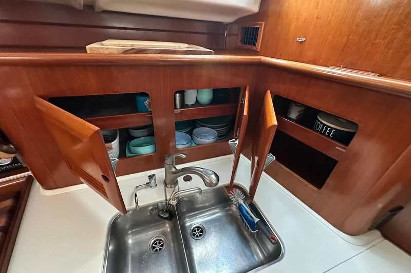 Slide: The Image of Galley kitchen in 2000 Beneteau 50 yacht with double sink and wooden cabinets. - 89