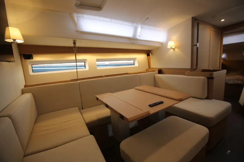 Slide: The Image of Interior of 2023 Jeanneau Sun Odyssey 490 yacht, featuring a cozy dining area with beige seating. - 14