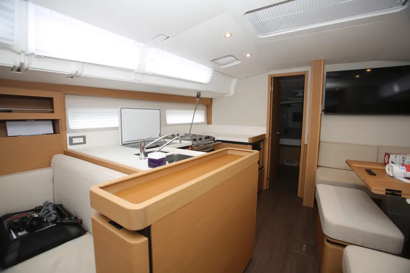 Slide: The Image of Interior of 2023 Jeanneau Sun Odyssey 490 yacht, featuring modern kitchen and seating area. - 15