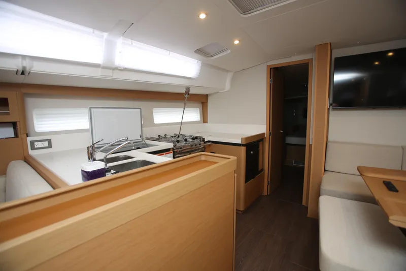 Slide: The Image of Interior of 2023 Jeanneau Sun Odyssey 490 yacht, featuring modern kitchen and seating area. - 16