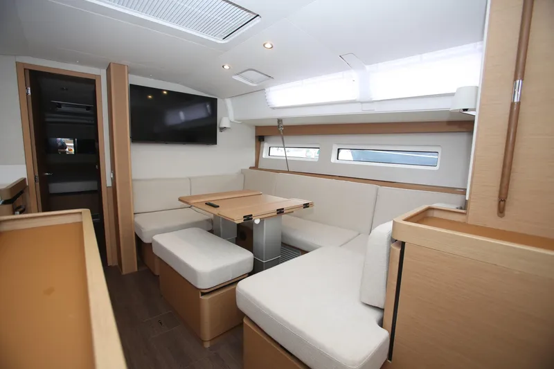 Slide: The Image of Interior of 2023 Jeanneau Sun Odyssey 490 yacht, featuring modern seating and a mounted TV. - 18