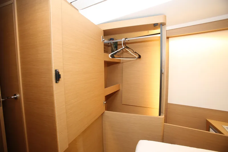 Slide: The Image of Interior of 2023 Jeanneau Sun Odyssey 490 yacht, featuring a wooden wardrobe with hangers. - 26
