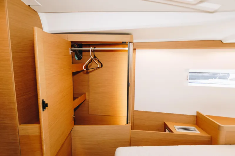 Slide: The Image of Interior of 2023 Jeanneau Sun Odyssey 490 yacht, featuring a wooden wardrobe and hangers. - 35