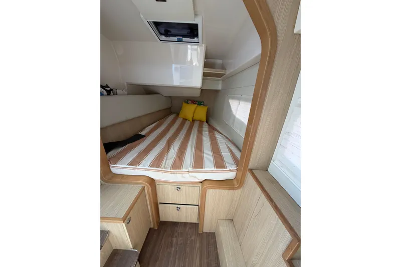 Slide: The Image of Interior cabin of 2018 Aquila 36 Sport with striped bedding and wooden accents. - 8