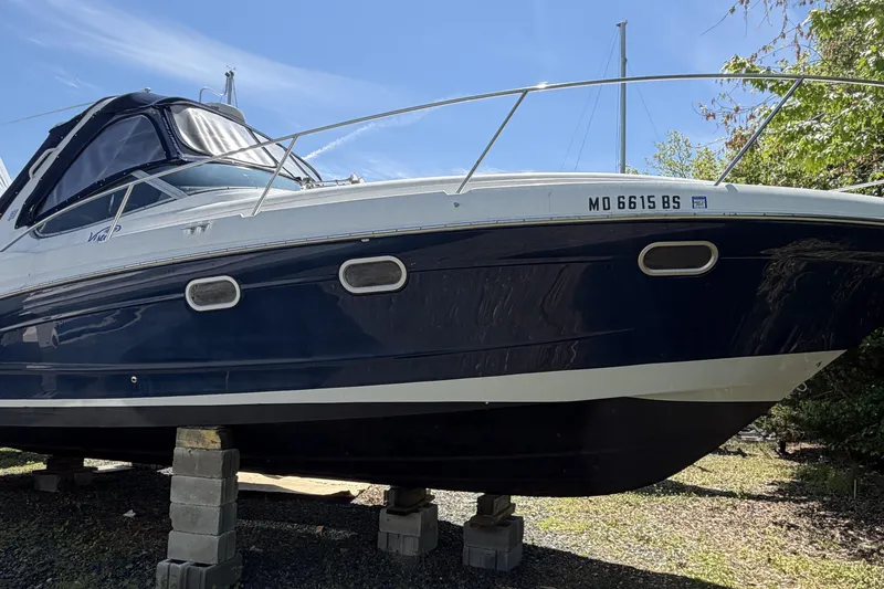 The Image of 2003 Four Winns 328 Vista boat on blocks, blue and white hull, sunny day. - 1