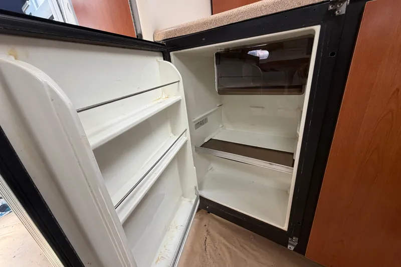Slide: The Image of Open refrigerator inside a 2003 Four Winns 328 Vista boat, showing empty shelves. - 23