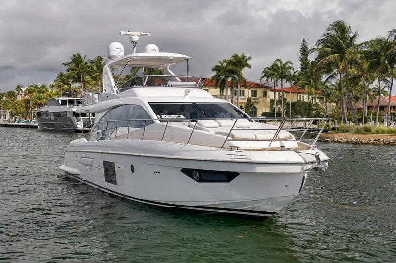 Slide: The Image of Luxury 2019 Azimut 55 yacht cruising near palm-lined waterfront homes. - 38