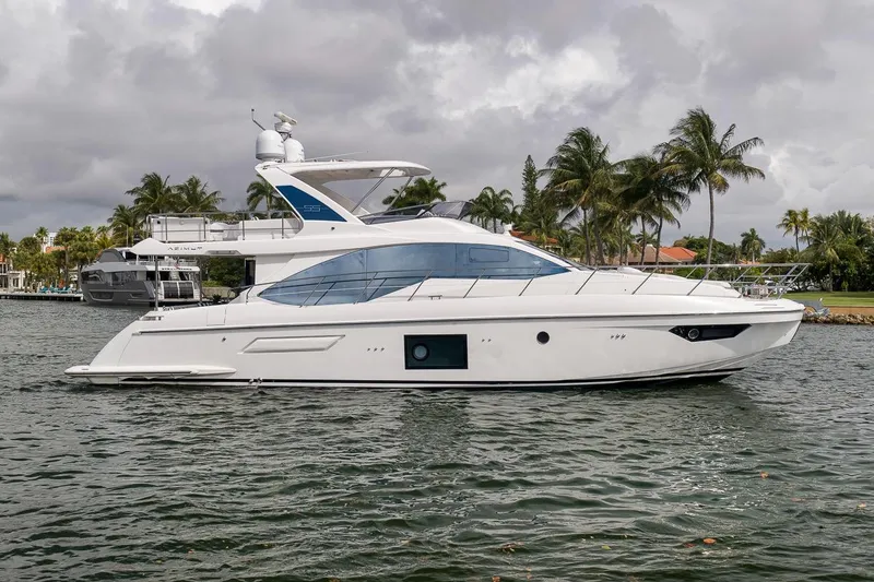 Slide: The Image of 2019 Azimut 55 yacht cruising on a scenic waterway with palm trees in the background. - 41