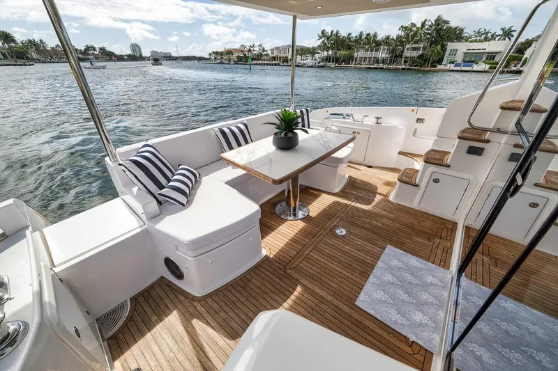 Slide: The Image of Luxurious 2019 Azimut 55 yacht deck with elegant seating, table, and scenic waterfront view. - 72