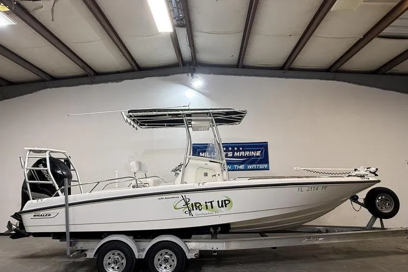 The Image of 2011 Boston Whaler 230 Dauntless boat on trailer in indoor showroom. - 0