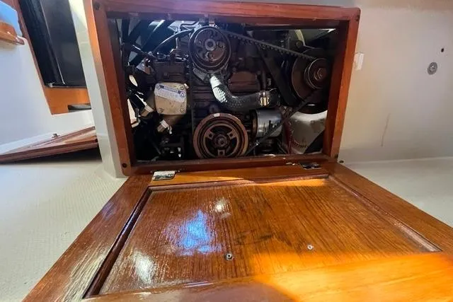 Slide: The Image of Engine compartment of a 1988 Catalina 30 sailboat, showcasing mechanical components and wooden paneling. - 12