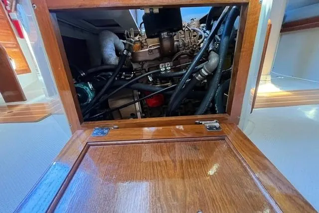 Slide: The Image of Engine compartment of a 1988 Catalina 30 sailboat, showcasing mechanical components and wooden access panel. - 14
