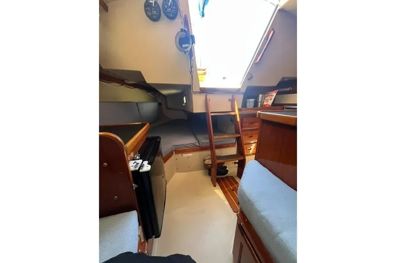 Slide: The Image of Interior of a 1988 Catalina 30 sailboat, featuring cozy seating and wooden cabinetry. - 26