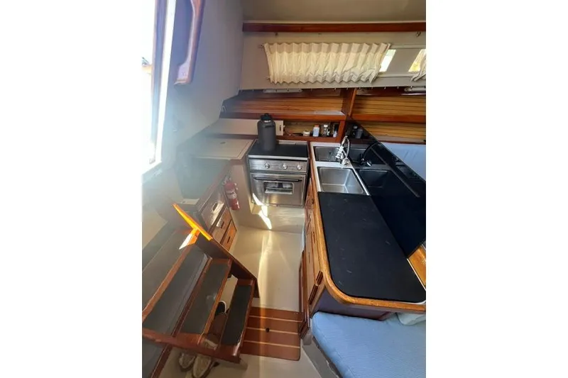 Slide: The Image of Interior of 1988 Catalina 30 sailboat kitchen with stove, sink, and wooden cabinetry. - 27