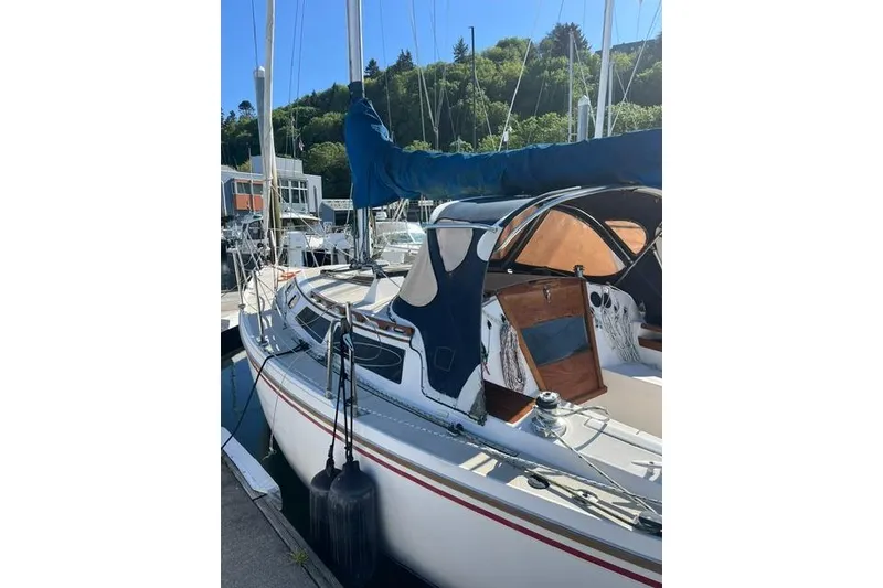 Slide: The Image of 1988 Catalina 30 sailboat docked, featuring a blue canopy and wooden accents. - 3
