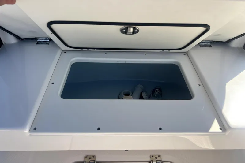 Slide: The Image of 2021 Robalo R272 Center Console storage compartment with open lid, showcasing interior space. - 25