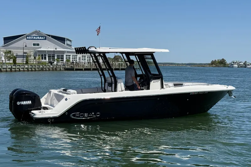 Slide: The Image of 2021 Robalo R272 Center Console boat on water near a restaurant, featuring Yamaha engine. - 5