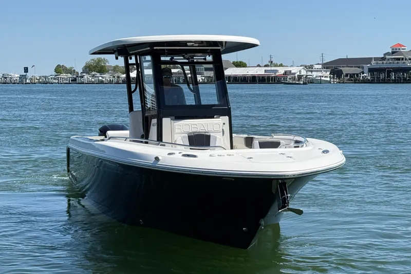 Slide: The Image of 2021 Robalo R272 Center Console boat on calm water, near a marina. - 7