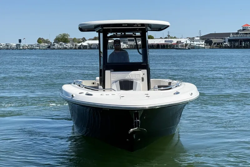 Slide: The Image of 2021 Robalo R272 Center Console boat on calm water, with marina in background. - 8