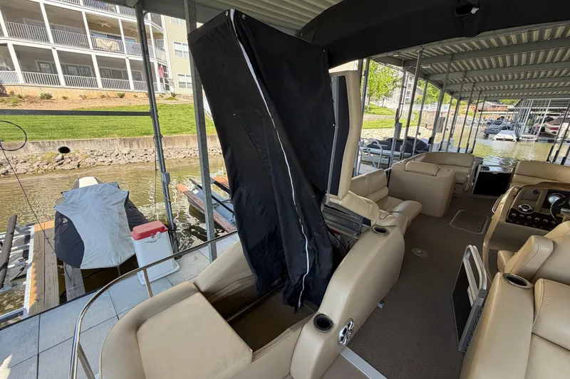 Slide: The Image of 2011 Bennington 2575QCW OB pontoon boat interior at dock, featuring beige seating. - 13