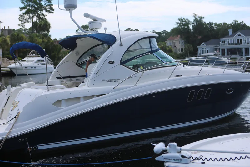 The Image of 2010 Sea Ray 390 Sundancer yacht docked in a marina, surrounded by waterfront homes. - 0