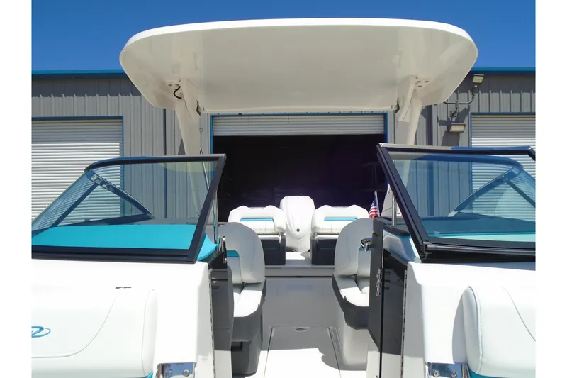 Slide: The Image of 2022 Regal LX6 boat interior with open cockpit and seating, docked near a warehouse. - 16