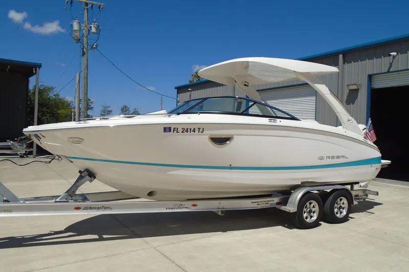 Slide: The Image of 2022 Regal LX6 boat on trailer, parked outside a warehouse. - 6