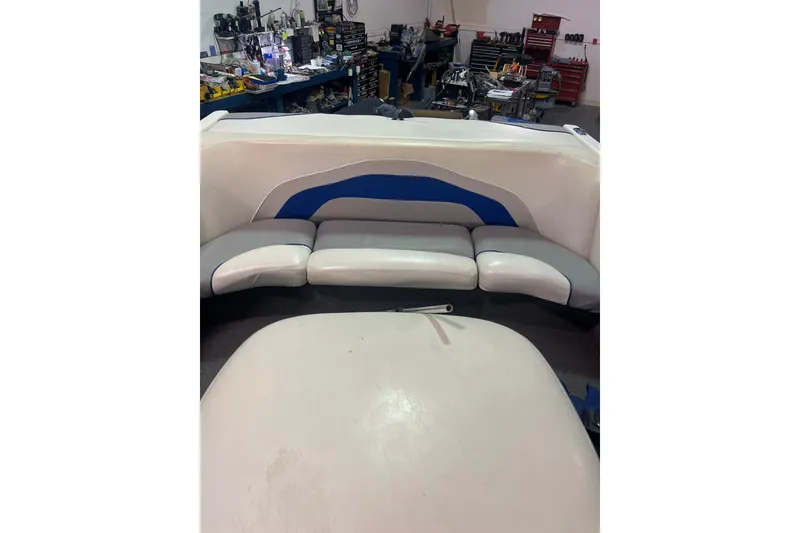 Slide: The Image of 2005 Malibu 21 Ride boat interior with white and blue seating in a workshop setting. - 4