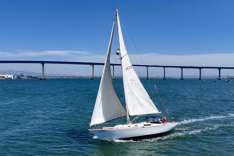 Slide: The Image of 1970 Morgan 42 MKI sailboat cruising under a clear blue sky near a bridge. - 2