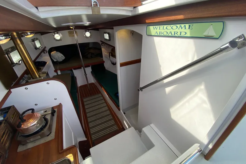 Slide: The Image of Interior of 2013 Devlin Onyx boat with cozy cabin and "Welcome Aboard" sign. - 13