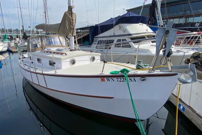 Slide: The Image of 2013 Devlin Onyx sailboat docked at marina, featuring classic design and white hull. - 2