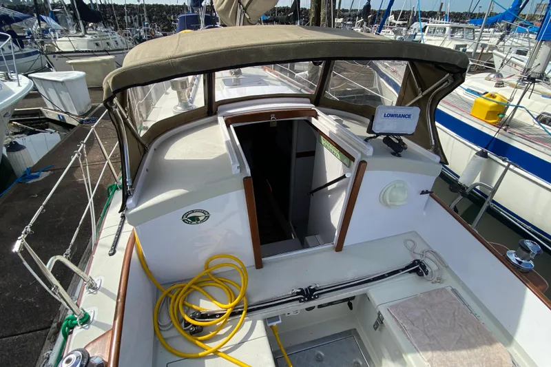 Slide: The Image of 2013 Devlin Onyx sailboat cockpit with canopy, docked at marina, featuring navigation equipment. - 6
