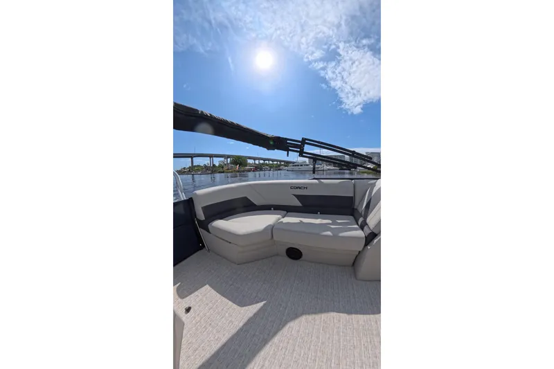 Slide: The Image of 2026 Coach 243 boat interior with cushioned seating under a sunny sky. - 12