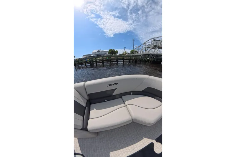 Slide: The Image of 2026 Coach 243 boat with sleek seating, dockside view, and blue sky. - 13