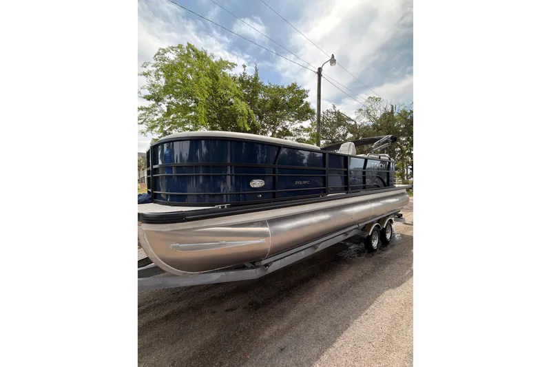 Slide: The Image of 2026 Coach 243 pontoon boat on trailer, parked outdoors under a cloudy sky. - 5