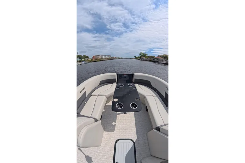 Slide: The Image of 2026 Coach 243 boat interior with seating and table on a scenic waterway. - 8