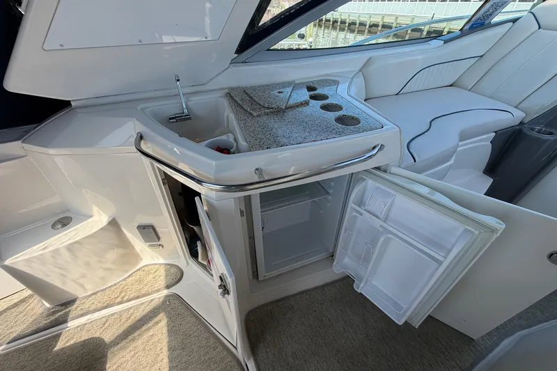 Slide: The Image of 2007 Monterey 330 Sport Yacht interior with open mini-fridge, sink, and seating area. - 15
