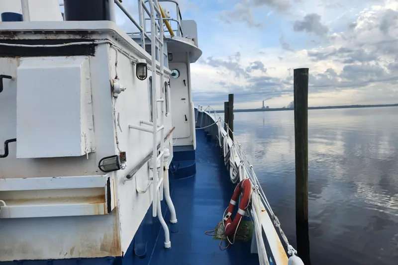 Slide: The Image of Side view of a 1960 Stord Verft 60 ship docked by calm waters under a cloudy sky. - 19