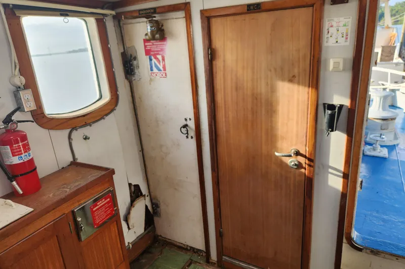 Slide: The Image of Interior of a 1960 Stord Verft 60 boat, featuring a wooden door and fire extinguisher. - 54
