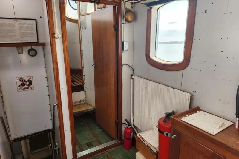 Slide: The Image of Interior of a 1960 Stord Verft 60 boat, featuring wooden doors and safety equipment. - 56