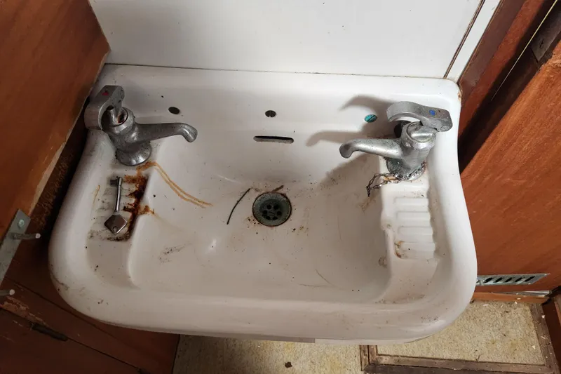 Slide: The Image of Old sink with dual faucets, rust stains, and a key, aboard a 1960 Stord Verft model 60. - 63