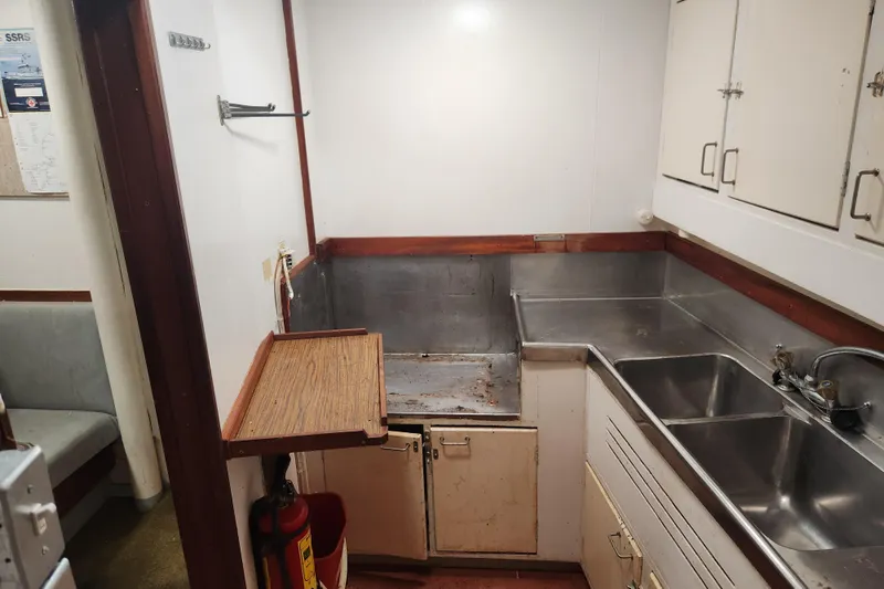 Slide: The Image of Small vintage ship kitchen with stainless steel sink, wooden accents, and storage cabinets, Stord Verft 1960. - 73