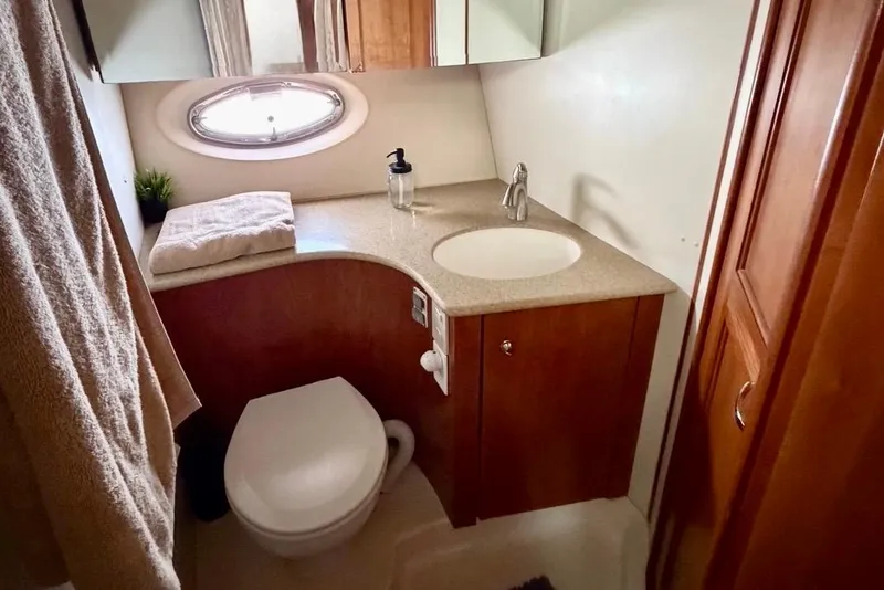 Slide: The Image of 2007 Silverton 36 Convertible yacht bathroom with sink, toilet, and porthole window. - 11