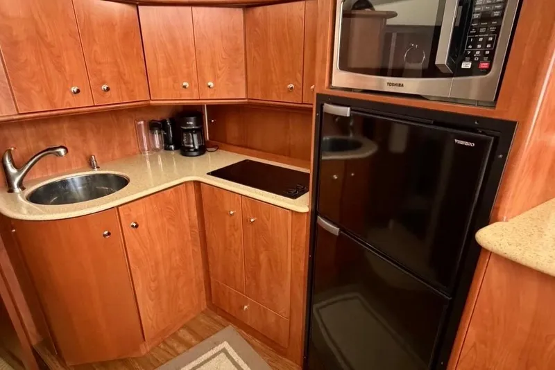 Slide: The Image of 2007 Silverton 36 Convertible yacht kitchen with wood cabinets, sink, stove, microwave, and fridge. - 9