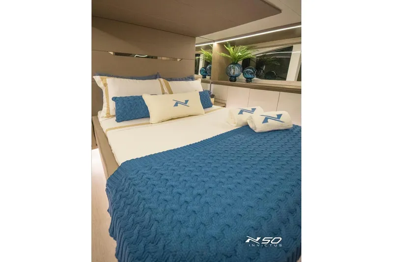 Slide: The Image of Luxurious bedroom interior of 2025 NX Boats NX50 Invictus HT with blue accents and elegant decor. - 11