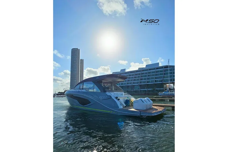 Slide: The Image of 2025 NX Boats NX50 Invictus HT yacht docked in sunny marina with modern buildings. - 18