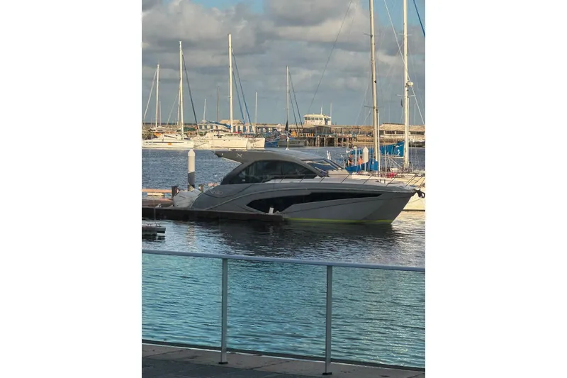 Slide: The Image of 2025 NX Boats NX50 Invictus HT yacht docked in a marina under cloudy skies. - 2