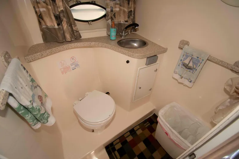 Slide: The Image of Compact bathroom in a 2000 Rinker Fiesta Vee 310 boat, featuring a toilet and sink. - 14