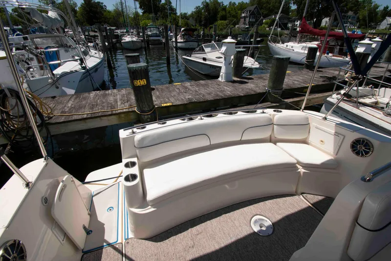 Slide: The Image of 2000 Rinker Fiesta Vee 310 boat interior with white seating at a marina dock. - 7