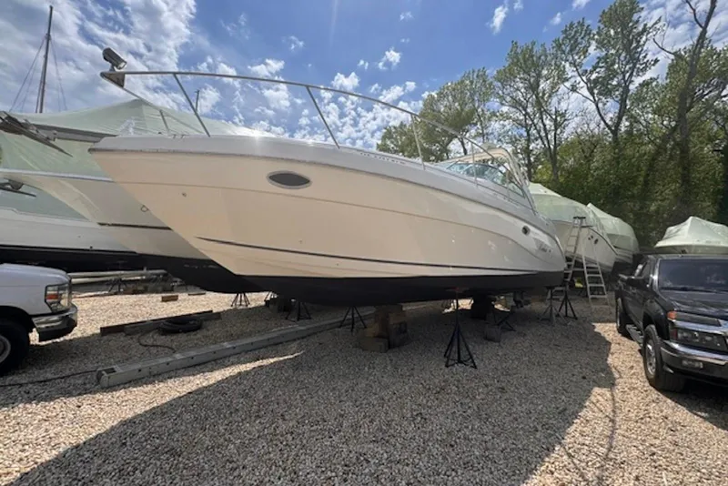 Slide: The Image of 2000 Rinker Fiesta Vee 310 boat on stands, surrounded by vehicles and trees. - 8